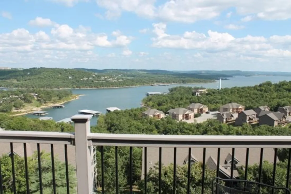 This image captures a sweeping lake view framed by rolling hills, with residential buildings and a dock area visible in the distance. The tranquil water and natural scenery evoke a sense of relaxation and serve as a reminder of the scenic beauty just outside the condo.