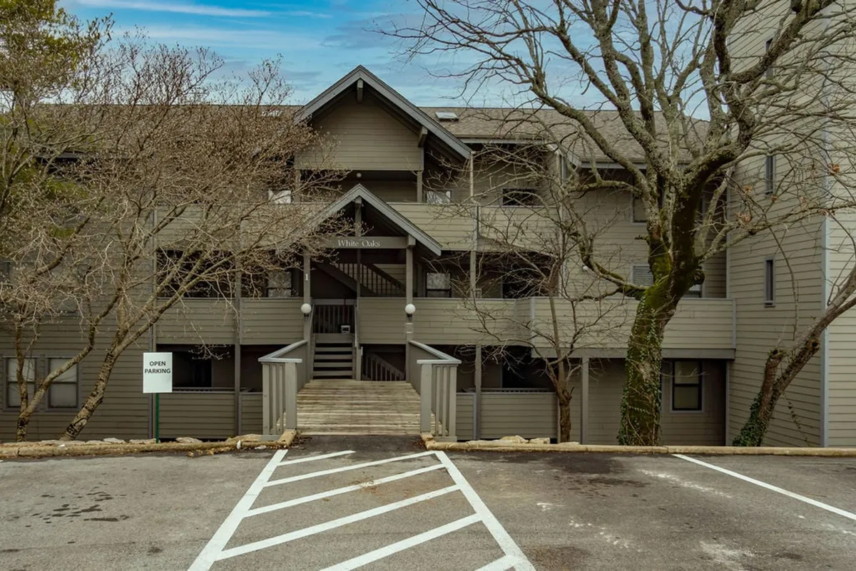 This exterior shot highlights the welcoming entrance steps and signage of the property, surrounded by tall trees, capturing the arrival experience and a sense of relaxation in nature. The image sets a tone of accessibility and makes clear the property's proximity to Branson's attractions.