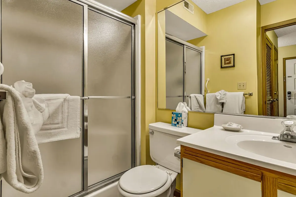 A fresh and inviting bathroom with a modern shower area, vanity, mirror, and toilet. The clean design and natural lighting create a spa-inspired atmosphere.