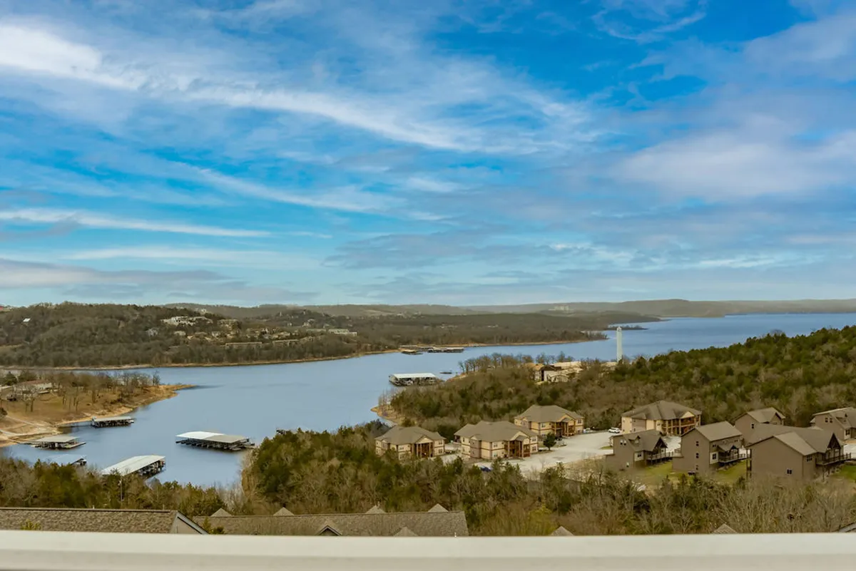 This image captures a sweeping view of Table Rock Lake surrounded by lush hills, dotted with residential buildings and docks. The tranquil scene embodies the serene beauty of lakeside living and offers a clear sense of the water-based activities available nearby, such as boating and fishing.